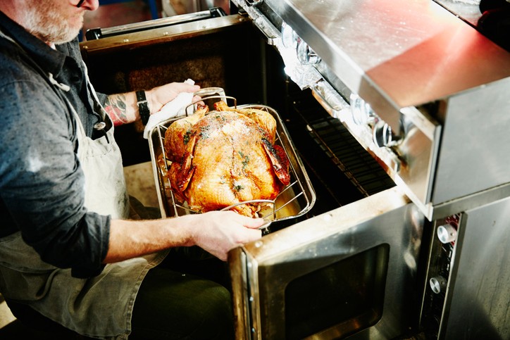 Man pulling cooked turkey out of oven