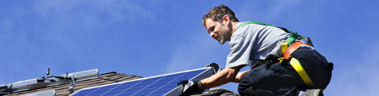 Technician installing residential rooftop solar pannels on house