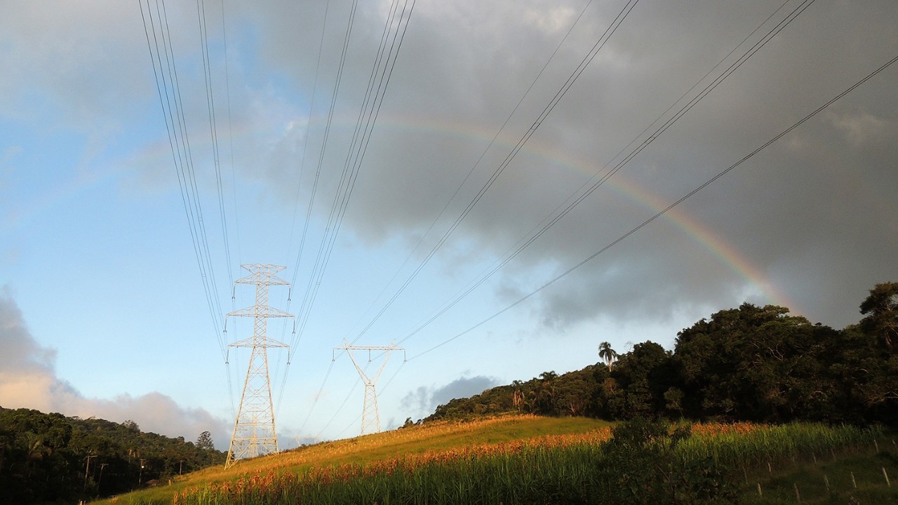 Transmission Towers across a field with rainbow in background