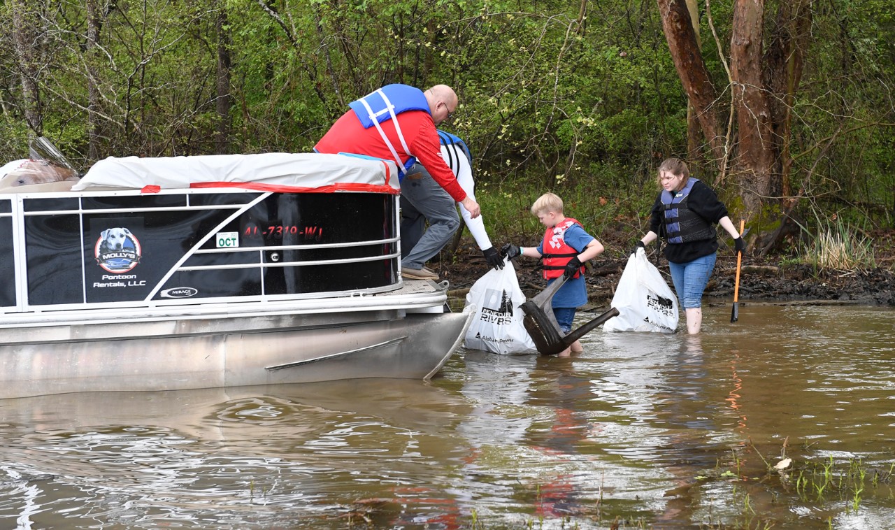 caucasian family cleaning up trash in the river 