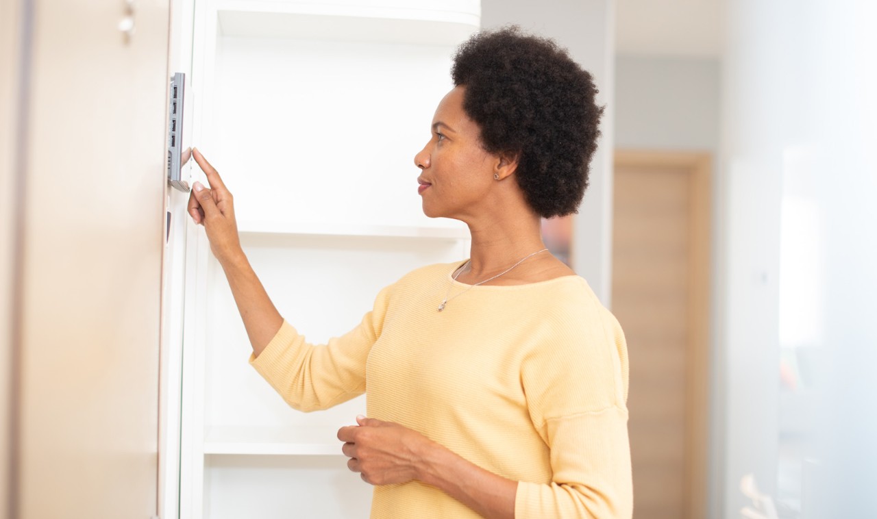 african american women adjusting thermostat 