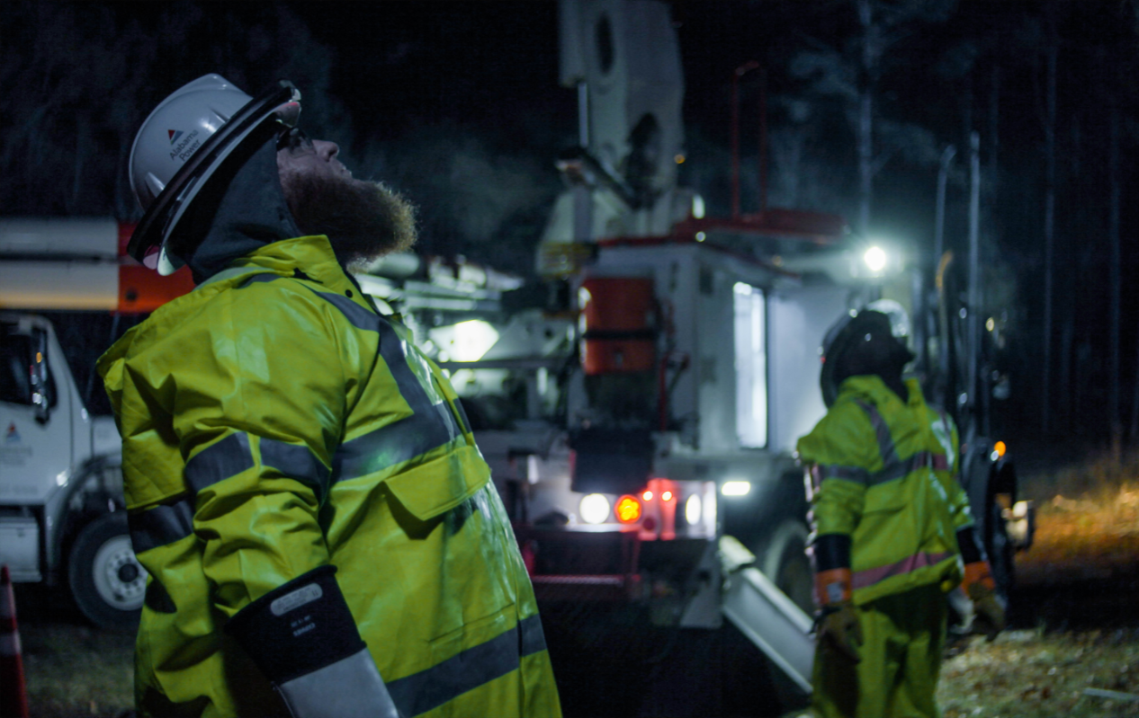 An Alabama Power lineman in bright yellow gear is hard at work in a bucket truck.