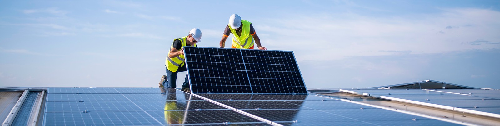 two men installing solar panels on a roof