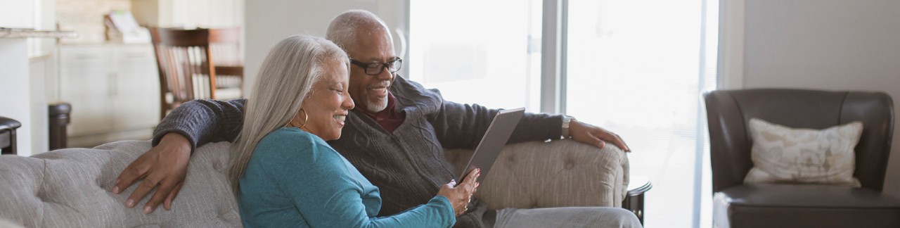 Couple on couch laughing while looking at tablet