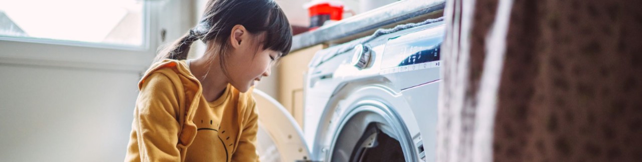 Lovely little girl unloading the washing machine
