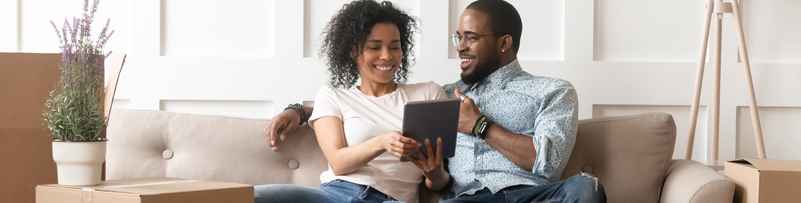 Couple on couch laughing while looking at tablet