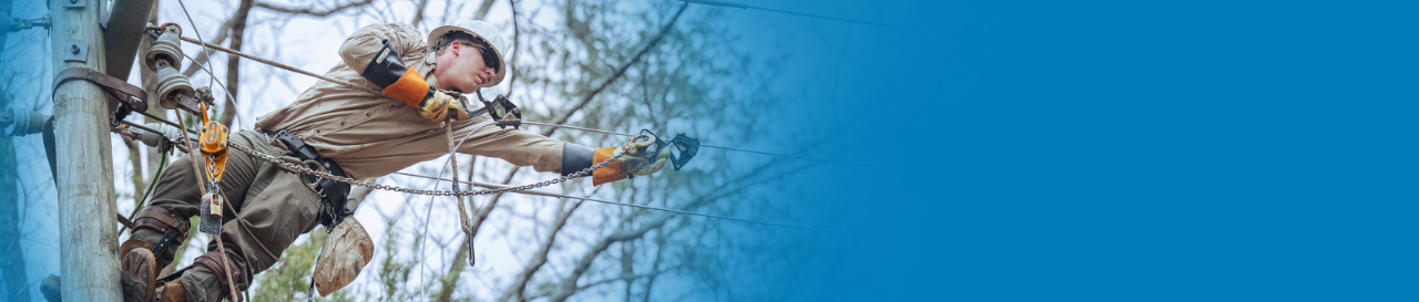An Alabama Power lineman at the top of a power pole works diligently to restore power.
