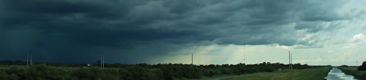 Severe weather moving into a rural area with power lines in the foreground.