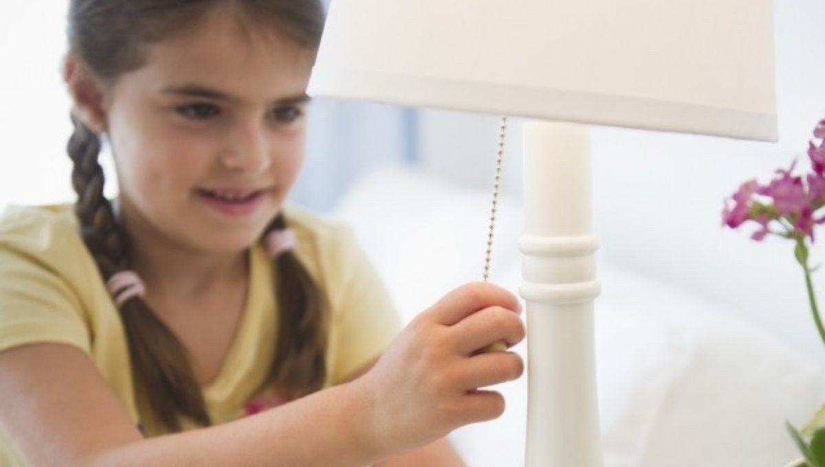 Child turning on table lamp via chain