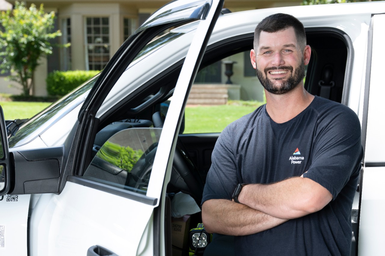 Alabama Power employee standing in front of car