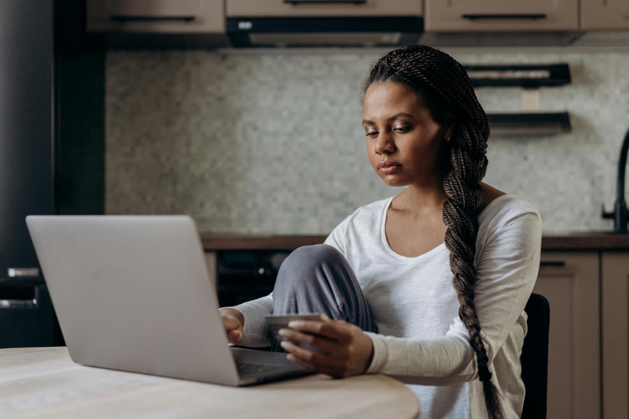 women holding up credit card working on laptop