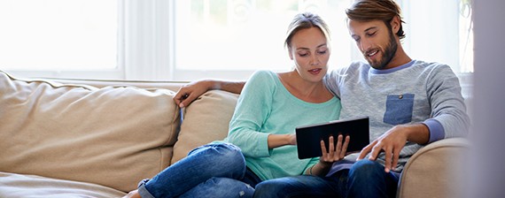 Pareja revisando la tableta en el sofá 