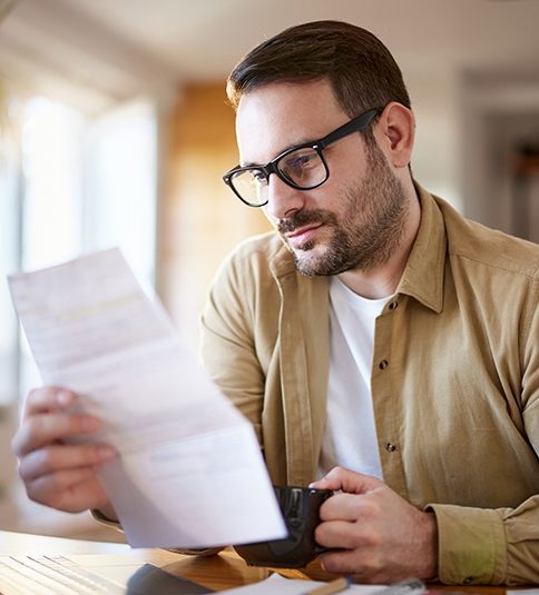 Young man drinking coffee while working on home finances.