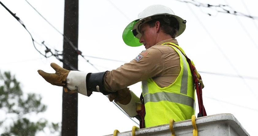 Alabama Power Electric Technician putting on gloves prior to fixing utility pole