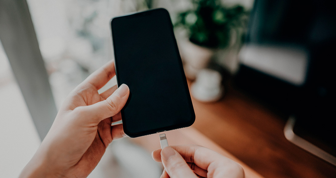 Woman's hand connecting smartphone to cable and getting charged 